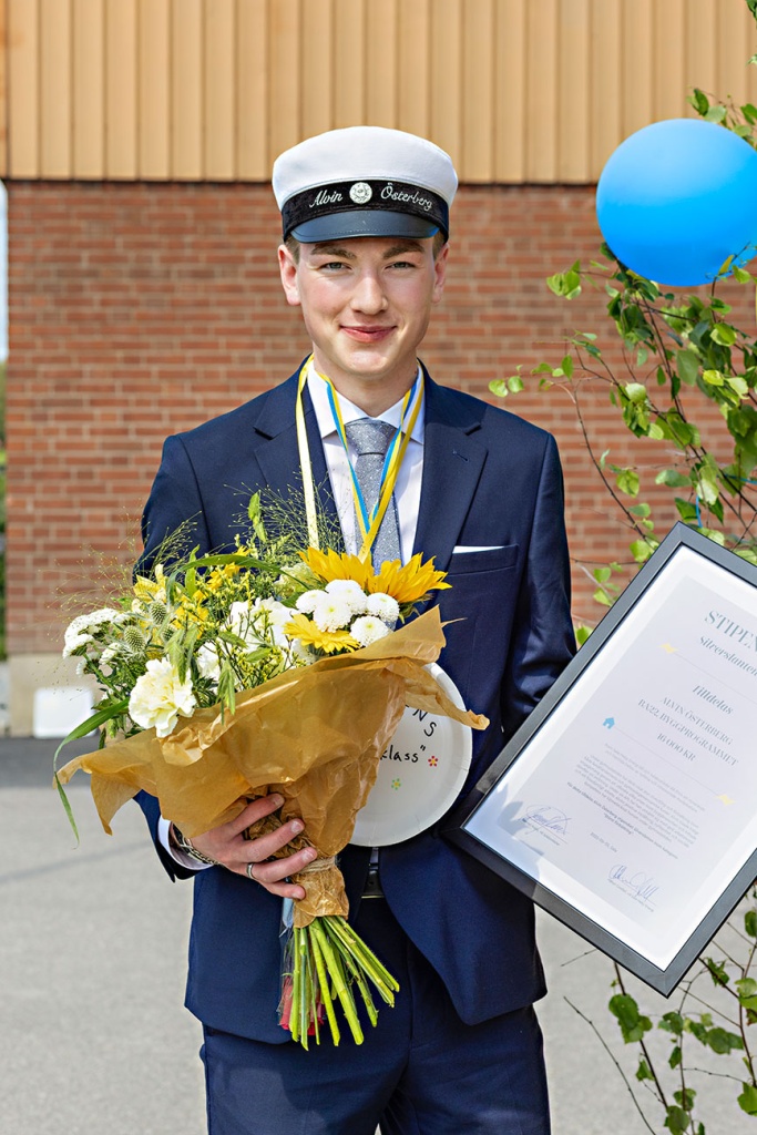 Alvin står med blommor och diplom utanför Ösbyskolan