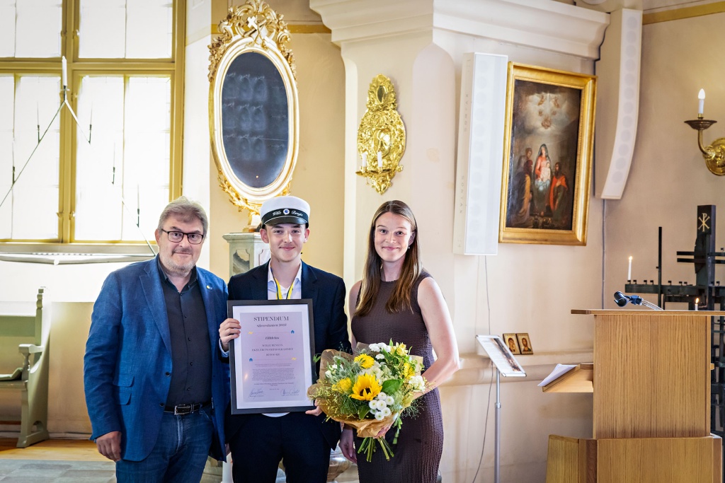 Stipendiat i kyrkan med diplom och blommor.